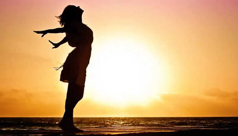 Femme heureuse sur une plage au coucher du soleil