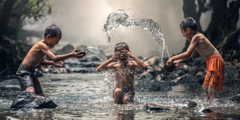 trois enfants hilares jouant dans l'eau