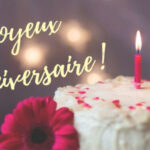 Gâteau d'anniversaire avec une bougie et une fleur mauve, et le texte joyeux anniversaire